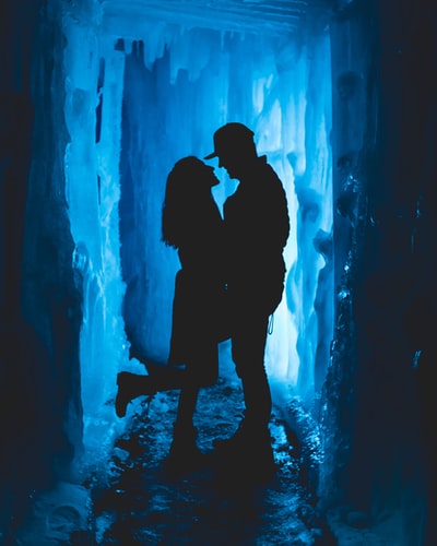 男人和女人面对彼此密切在冰洞

